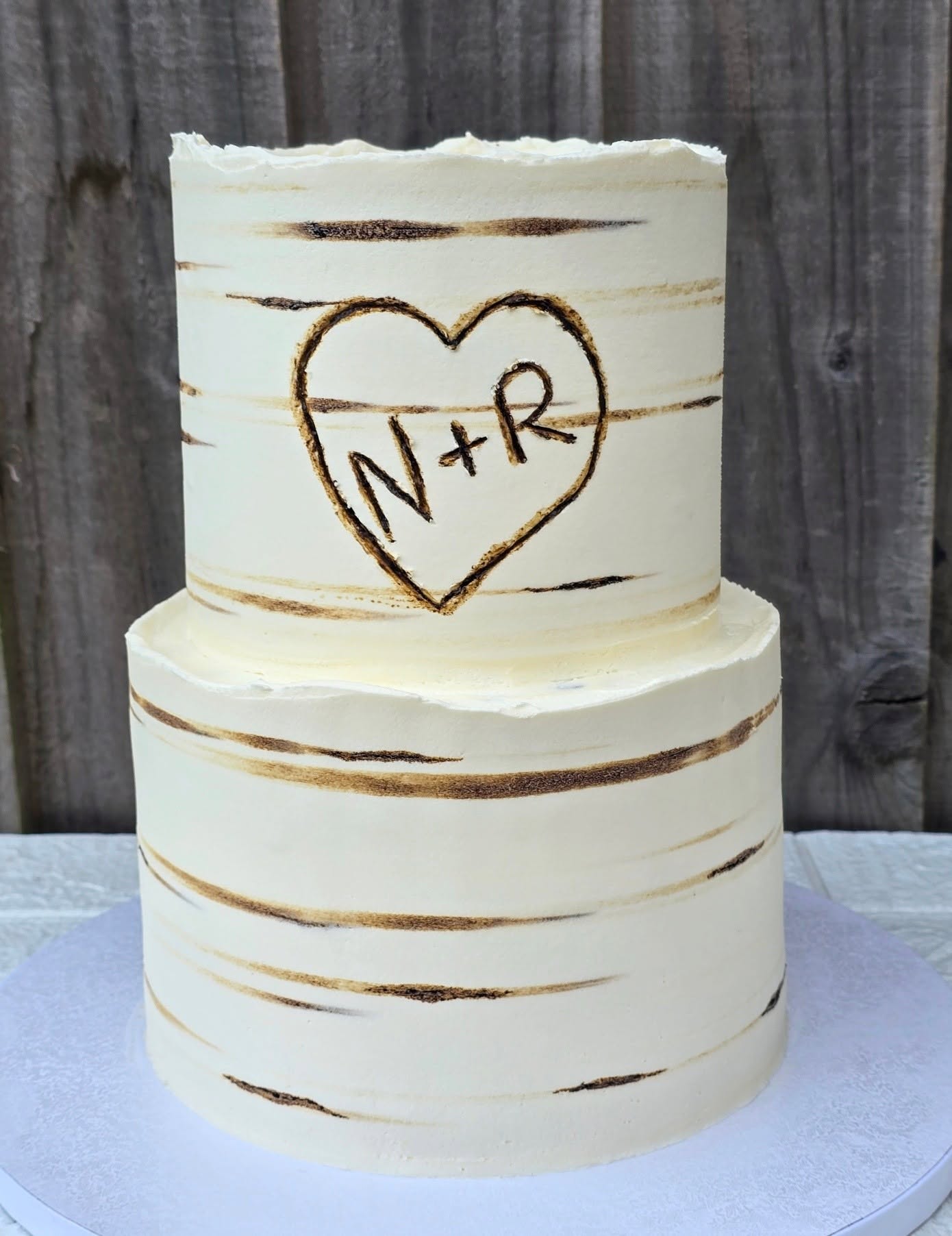 An elegant two-tier cake with gold accents and a heart with initials.