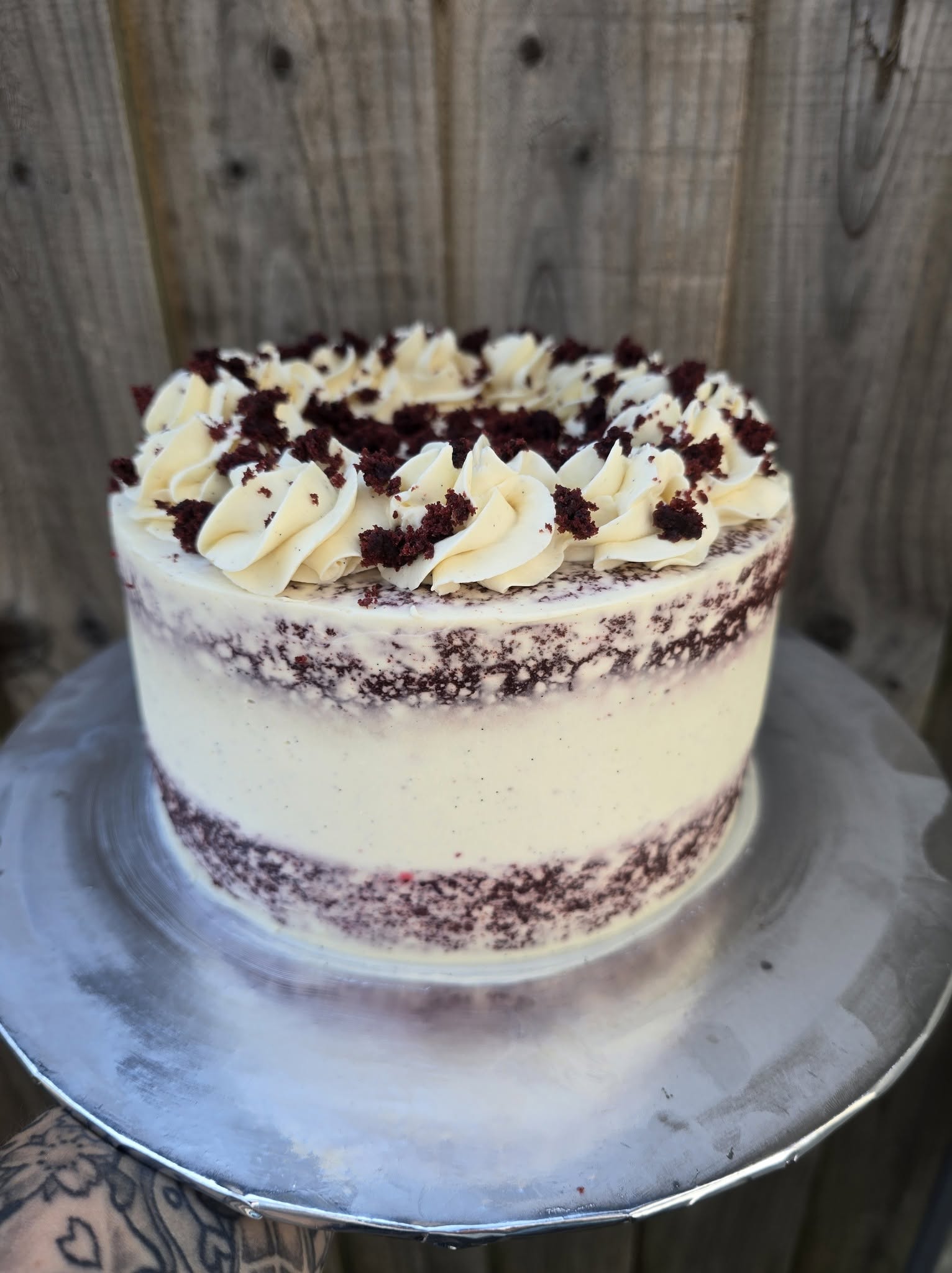 A red velvet cake cheesecake with piped cream and chocolate details.